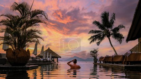 Foto de Piscina de lujo en complejo tropical, vacaciones relajantes en las islas Seychelles. La Digue, Joven al atardecer en la piscina Seychelles en vacaciones - Imagen libre de derechos