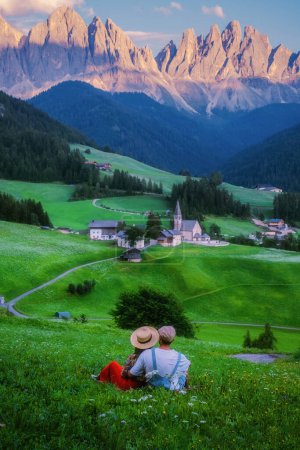 Photo for Couple viewing the landscape of Santa Maddalena Village in Dolomites Italy, Santa Magdalena village magical Dolomites mountains, Val di Funes valley, Trentino Alto Adige region, South Tyrol, Italy - Royalty Free Image