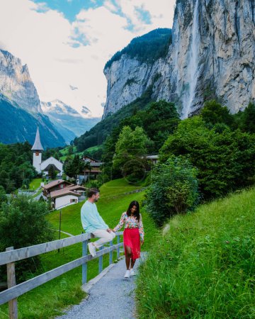 Foto de Una pareja visita el pueblo de Lauterbrunnen, valle de Lauterbrunnen en los Alpes suizos, Suiza. Hombre caucásico y mujer asiática de vacaciones en Suiza - Imagen libre de derechos