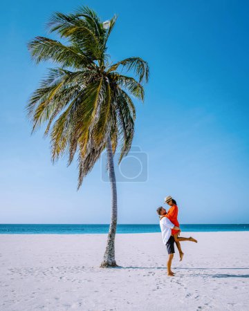 Téléchargez les photos : Eagle Beach Aruba, Palmiers sur le rivage d'Eagle Beach à Aruba, un couple d'hommes et de femmes sur la plage d'Aruba - en image libre de droit