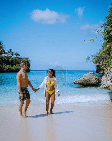 Téléchargez les photos : Couple visiter Playa Lagun Beach Cliff Curaçao, Lagun Beach Curaçao une petite île dans les Caraïbes, couple hommes et femmes d'âge moyen en vacances Curaçao visiter la plage - en image libre de droit