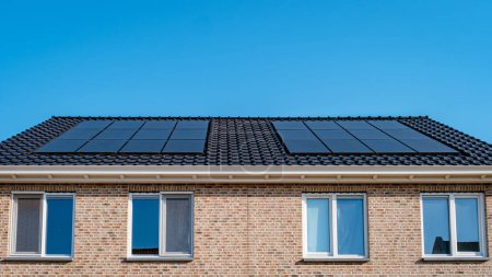 Téléchargez les photos : Maisons nouvellement construites avec des panneaux solaires fixés sur le toit contre un ciel ensoleillé, nouveaux bâtiments avec des panneaux solaires noirs. Zonnepanelen, Zonne energie, Traduction : Panneau solaire Énergie solaire. Pays Bas - en image libre de droit