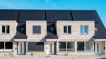 Photo for Newly build houses with solar panels attached on the roof against a sunny sky, new buildings with black solar panels. Zonnepanelen, Zonne energie, Translation: Solar panel Sun Energy. Netherlands - Royalty Free Image