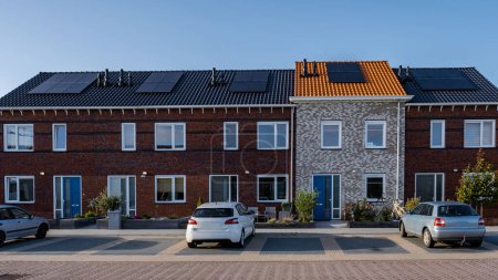 Neu gebaute Häuser mit Sonnenkollektoren auf dem Dach gegen den sonnigen Himmel, Neubauten mit schwarzen Sonnenkollektoren. Zonnepanelen, Zonne energie, Übersetzung: Sonnenkollektor Sun Energy. Wohnungsmarkt