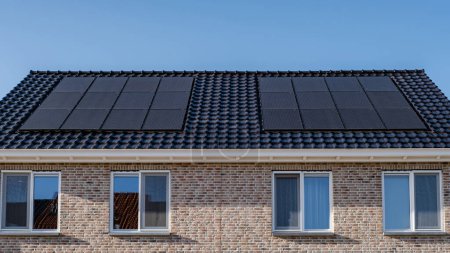 Téléchargez les photos : Maisons nouvellement construites avec des panneaux solaires fixés sur le toit contre un ciel ensoleillé, nouveaux bâtiments avec des panneaux solaires noirs. Zonnepanelen, Zonne energie, Traduction : Panneau solaire Énergie solaire. Marché du logement - en image libre de droit