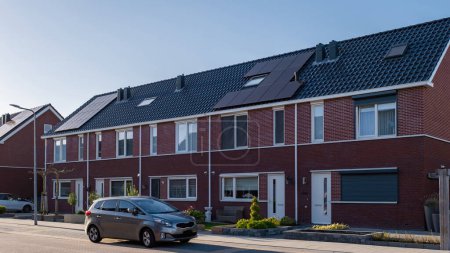 Foto de Casas de nueva construcción con paneles solares unidos en el techo contra un cielo soleado, el mercado de la vivienda en los Países Bajos - Imagen libre de derechos