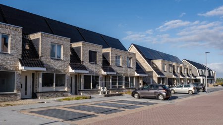Neugebaute Häuser mit Sonnenkollektoren auf dem Dach vor sonnigem Himmel, Wohnungsmarkt in den Niederlanden