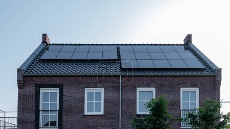 Foto de Casas de nueva construcción con paneles solares unidos en el techo contra un cielo soleado, energía verde de energía renovable - Imagen libre de derechos