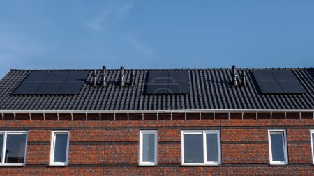 Téléchargez les photos : Maisons nouvellement construites avec des panneaux solaires fixés sur le toit contre un ciel ensoleillé, énergie renouvelable énergie verte - en image libre de droit