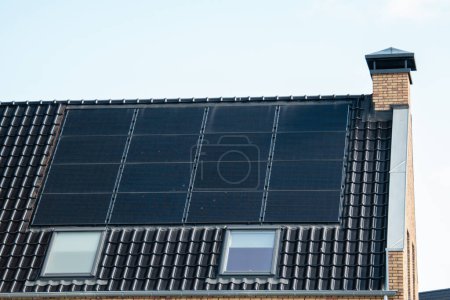 Foto de Casas de nueva construcción con paneles solares unidos en el techo contra un cielo soleado, energía verde de energía renovable - Imagen libre de derechos