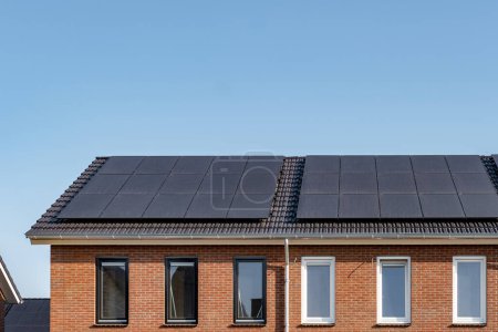 Téléchargez les photos : Maisons nouvellement construites avec des panneaux solaires fixés sur le toit contre un ciel ensoleillé, énergie renouvelable énergie verte - en image libre de droit