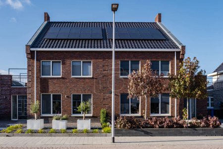 Newly build houses with solar panels attached on the roof against a sunny sky, new buildings with black solar panels. Zonnepanelen, Zonne energie, Translation: Solar panel Sun Energy. Housing market