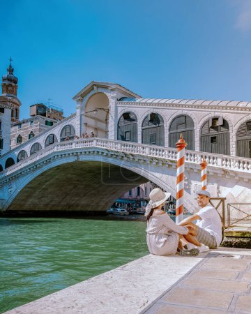 Foto de Venecia Italia pareja de hombres y mujeres en un viaje a Venecia, hombres y mujeres en el paseo marítimo mirando el famoso puente de Rialto en Venecia Italia. Europa - Imagen libre de derechos