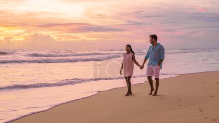 Photo for Sunset on the beach of Phuket Thailand, and colorful sunset during monsoon rain season at the beach. Asian women and Caucasian men watching the sunset - Royalty Free Image