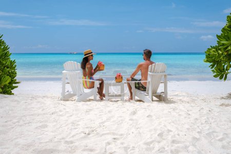 Paar Männer und Frauen am Strand mit einem Kokosgetränk Praslin Seychellen tropische Insel mit weißen Stränden und Palmen, der Strand von Anse Volbert Seychellen.
