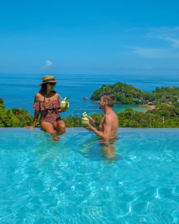 Foto de Un par de hombres europeos y una mujer asiática en una piscina infinita en Tailandia con vistas al océano, unas vacaciones de lujo en Tailandia - Imagen libre de derechos