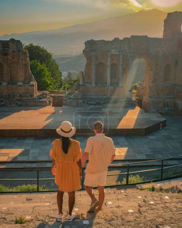 Foto de Taormina Sicilia, pareja observando la puesta de sol en las Ruinas del Teatro Griego Antiguo en Taormina, Sicilia. pareja mediana edad en vacaciones Sicilia - Imagen libre de derechos