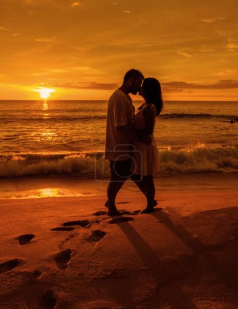 Photo for Couple watching the sunset on a beach in Phuket Thailand. Men and women during sunset on the beach with orange-red color sky - Royalty Free Image