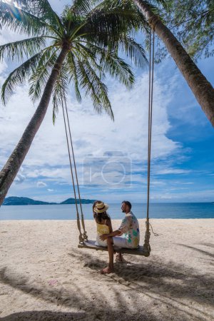 Foto de Couple on a swing on the beach with palm trees in Phuket Thailand. men and women on a swing at a tropical beach - Imagen libre de derechos