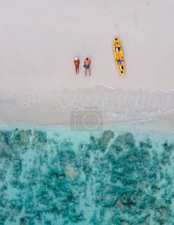 Foto de Drone view at couple laying down on the beach of Koh Phi Phi Thailand during vacation with kayak. - Imagen libre de derechos