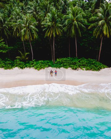Foto de Drone aerial view at couple on the beach at Freedom beach in Phuket Thailand during vacation, top view at tropical beach with people on the beach - Imagen libre de derechos