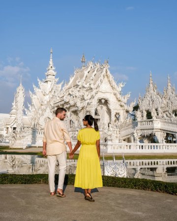 Téléchargez les photos : A couple visits the White Temple Chiang Rai Thailand, Wat Rong Khun, aka The White Temple, in Chiang Rai, Thailand. Asian women and Caucasian men visit a temple - en image libre de droit