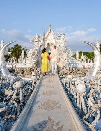 Téléchargez les photos : A couple visits the White Temple Chiang Rai Thailand, Wat Rong Khun, aka The White Temple, in Chiang Rai, Thailand. Asian women and Caucasian men visit a temple - en image libre de droit
