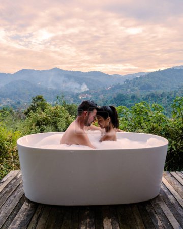 Foto de A couple of men and women in a bathtub homestay in Northern Thailand men and women relaxing in bath during vacation - Imagen libre de derechos