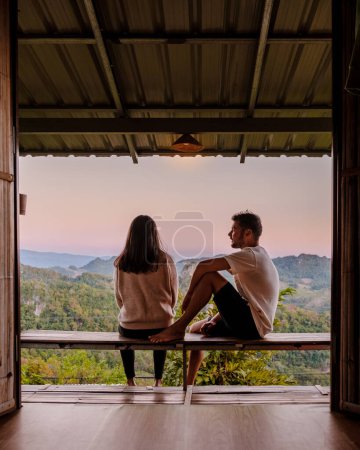 Téléchargez les photos : Couple watching the sunrise at Mae Hong Son mountains in Thailand, Ban Jabo Noodle house, Pha Mok Baan Jabo, Morning mist Viewpoint Phu Pha Mok Baan Jabo - en image libre de droit