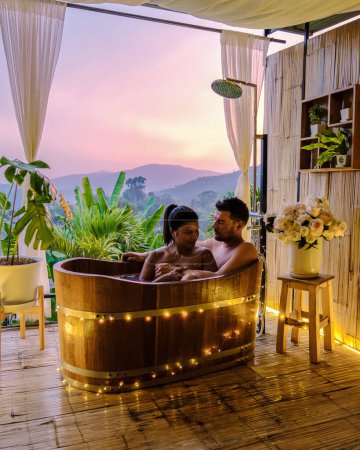 Foto de A couple of men and women in a bathtub in the evening during sunset, a couple in a bathtub. - Imagen libre de derechos