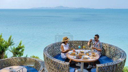 Photo for Couple having lunch at a restaurant looking out over the ocean of Pattaya Thailand, man and woman having dinner in a restaurant by the ocean in Pattaya. - Royalty Free Image