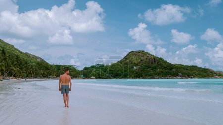 Foto de Cote dOr Beach Praslin Seychelles, young mid age men in swim short walking on the beach during vacation Seychelles tropical Island, white guy on the beach during holiday Praslin Seychelles - Imagen libre de derechos