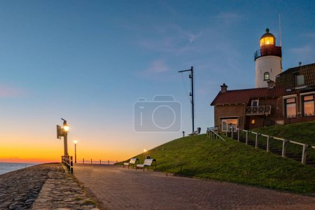 Photo for Urk Flevoland Netherlands sunset at the lighthouse and harbor of Urk Holland. Traditional Fishing village Urk. Beautiful sunset during the evening - Royalty Free Image