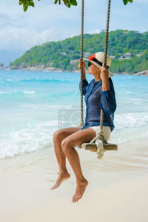Photo for Young women at a swing on a tropical beach in Mahe Tropical Seychelles Islands. - Royalty Free Image
