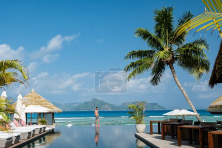 Téléchargez les photos : Young men at a swimming pool at a luxury hotel, a Luxury swimming pool in a tropical resort - en image libre de droit