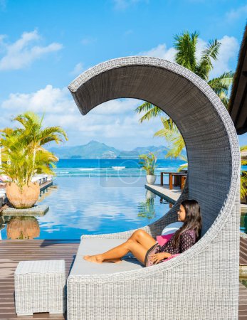 Téléchargez les photos : Asian women at a swimming pool at a luxury hotel, sun bed, and umbrella. - en image libre de droit
