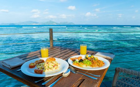 Photo for Breakfast table with a view over a turquoise colored ocean La Digue Seychelles Islands. - Royalty Free Image