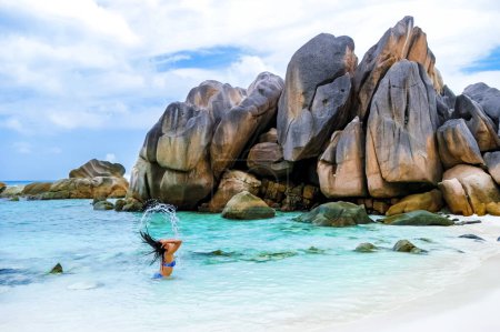 Téléchargez les photos : Women swimming at Anse Cocos beach with huge granite boulders at La Digue Seychelles Islands. - en image libre de droit