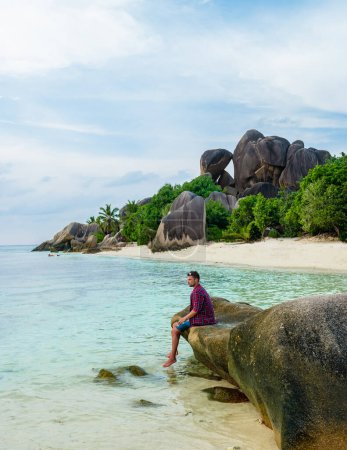 Téléchargez les photos : Young men at a white tropical beach Anse Source dArgent beach La Digue Seychelles Islands. - en image libre de droit