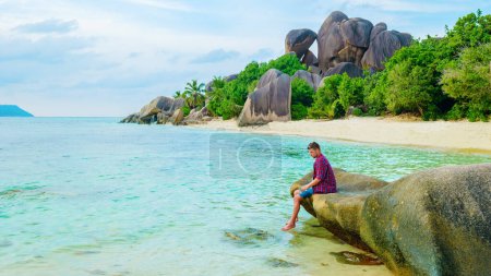 Téléchargez les photos : Young men at a white tropical beach Anse Source dArgent beach La Digue Seychelles Islands. - en image libre de droit