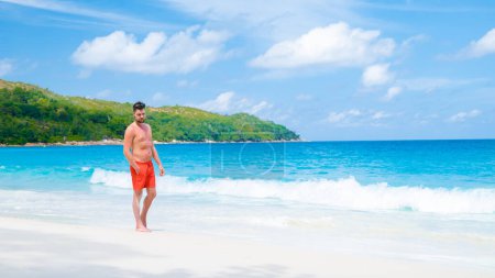 Photo for Young men in a swim short at Anse Lazio beach with turquoise colored ocean Praslin Seychelles Islands on a sunny day - Royalty Free Image