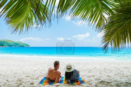 Téléchargez les photos : Couple relaxant sous un palmier sur une plage tropicale blanche Anse Lazio Praslin Tropical Seychelles Islands. - en image libre de droit