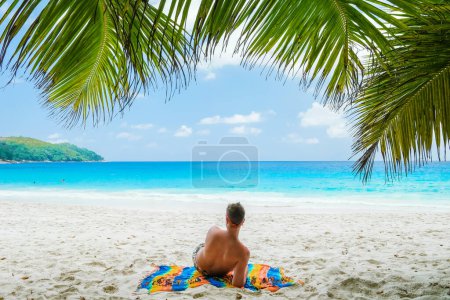 Photo for Young men in a swim short relaxing at Anse Lazio beach with turquoise colored ocean Praslin Seychelles Islands. - Royalty Free Image