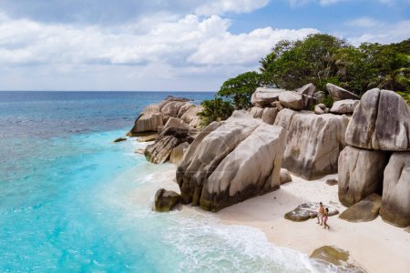 Téléchargez les photos : Young couple men and woman at a tropical beach in the Seychelles Cocos Island, drone view from above - en image libre de droit