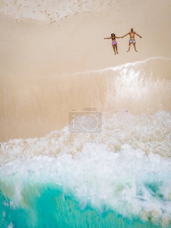 Téléchargez les photos : Man and woman laying down on a tropical beach, Drone view from above at a tropical beach in the Seychelles Cocos Island - en image libre de droit