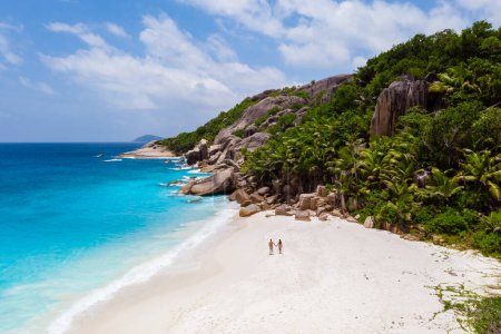 Téléchargez les photos : Couple men and woman walking at a tropical beach, Drone view from above Seychelles Cocos Island. - en image libre de droit