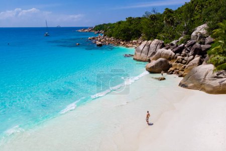 Téléchargez les photos : Young men on a white beach with turquoise colored ocean, Drone view from above at Anse Lazio beach Praslin Island Seychelles. - en image libre de droit
