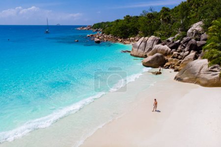 Photo for Young man on a white beach with turquoise colored ocean, Drone view from above at Anse Lazio beach Praslin Island Seychelles. - Royalty Free Image