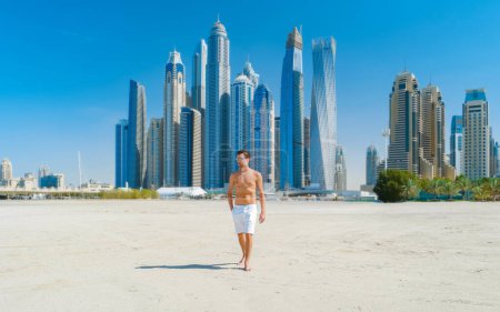 Téléchargez les photos : Jeune homme en short de bain sur la plage de Dubaï, Jumeirah beach Dubaï Émirats arabes unis par une journée ensoleillée. - en image libre de droit