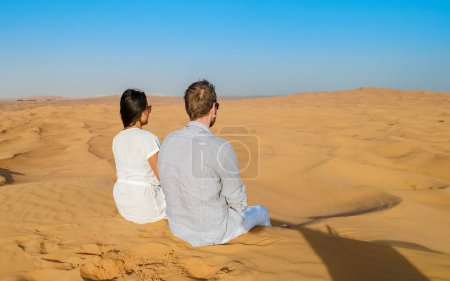 Photo for Couple on a Safari trip to the Sand dunes of Dubai United Arab Emirates, sand desert on a sunny day in Dubai. - Royalty Free Image